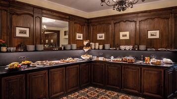 A large, dark wood-paneled kitchen with a long counter, various food items, and framed pictures on the walls.