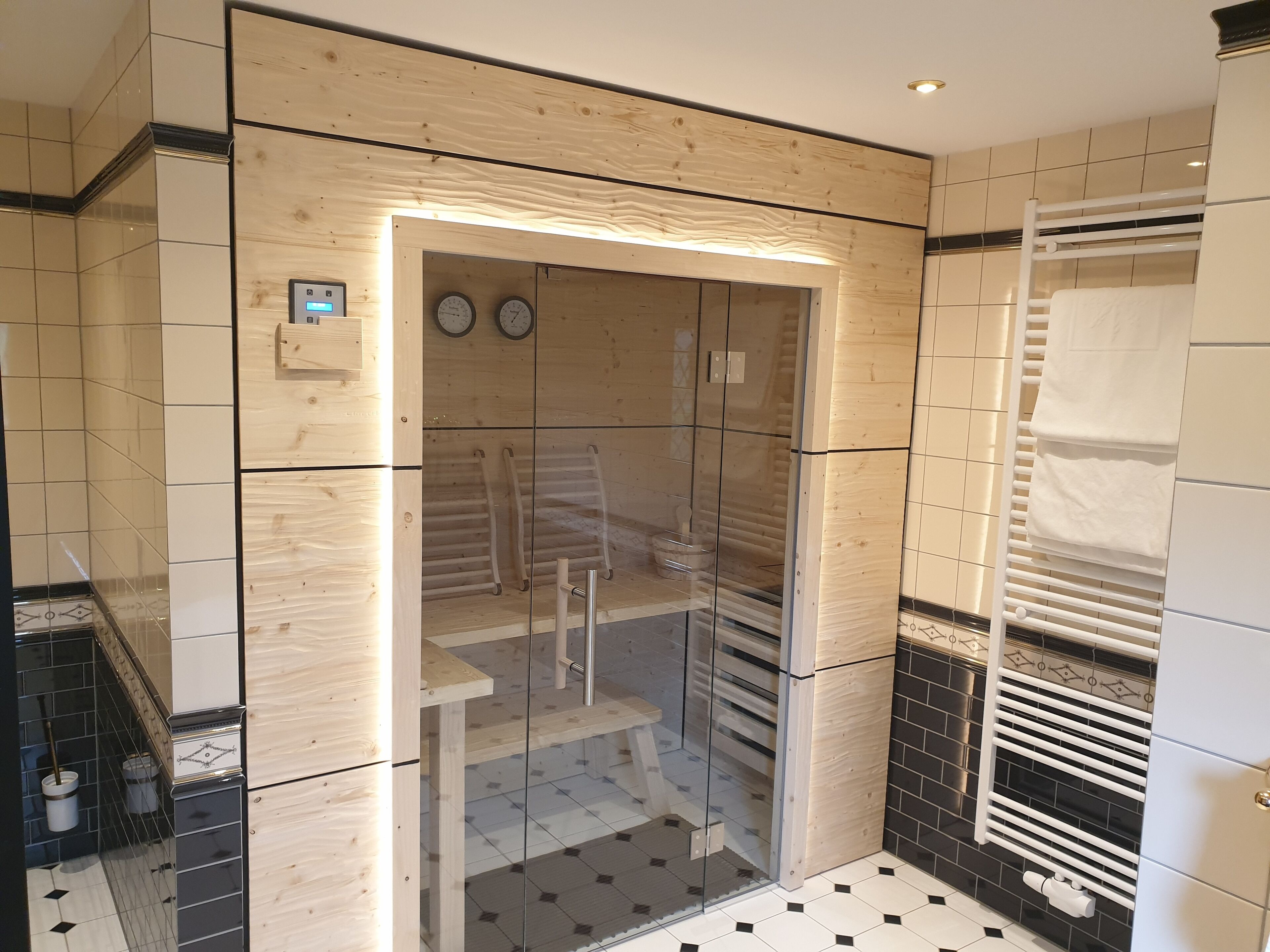 A modern bathroom with a glass-enclosed shower, wooden paneling, and a tiled floor.