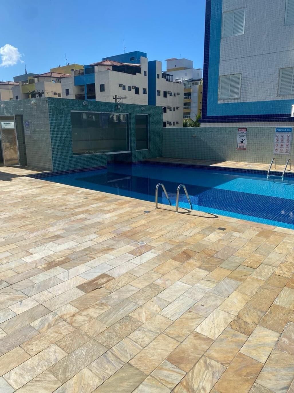 A rooftop swimming pool with tiled flooring and a clear blue pool.