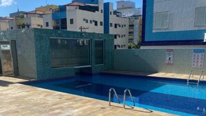 Ein Dachpool mit gefliestem Boden und klarem, blauem Wasser.