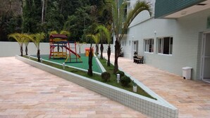 Ein Innenhof mit Kinderspielplatz, Palmen und einem Gebäude mit Kachelwänden.