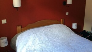 A hotel room with a wooden headboard, a white bedspread, and two wall-mounted lamps. - Beautiful apartment with mountain views (Saint-Lary-Soulan)