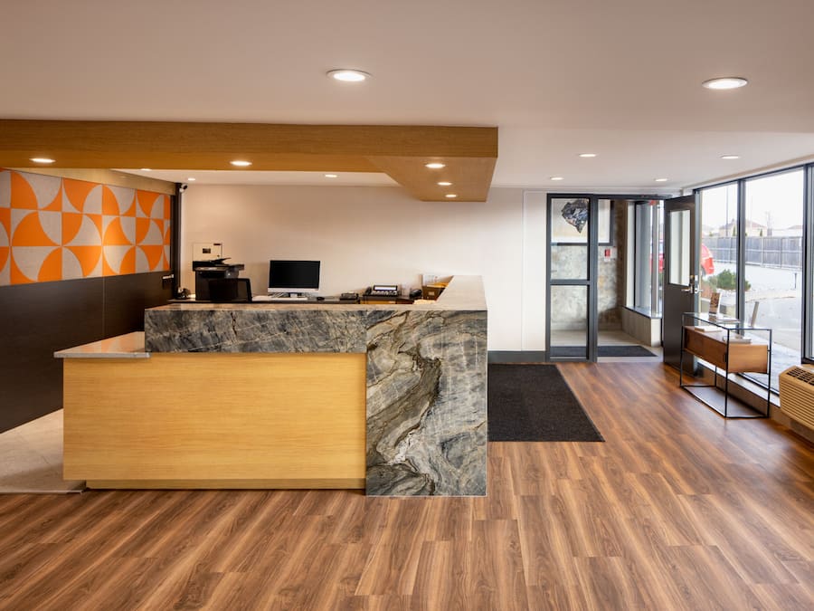 A modern reception area with a marble counter, wooden reception desk, and a large window offering a view of the outside.