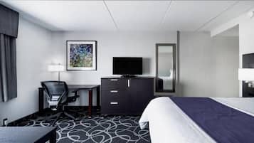 A hotel room with a bed, a desk, a chair, a television, and a mirror.