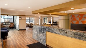 A modern reception area with a marble counter, wooden flooring, and seating arrangements.