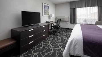 Une chambre d’hôtel comprenant un lit, un bureau avec un ordinateur, une télévision et une chaise.