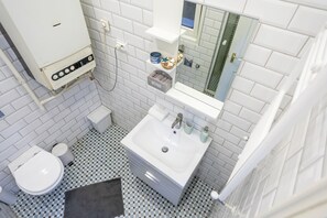A bathroom with a white toilet, a sink with a mirror above it, and a tiled floor. - Lie On Me Lazy Simon (Budapest)