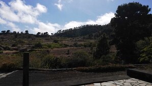 Ein gepflasterter Weg führt zu einer Aussichtsplattform mit Blick auf eine hügelige Landschaft und Bäume.
