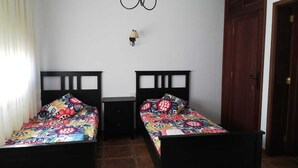 Ein Zimmer mit zwei Betten, einer Kandelaber, einem kleinen Tisch und einer Tür.