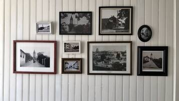 Un mur orné de plusieurs photographies en noir et blanc, encadrées, représentant différents bâtiments et rues.