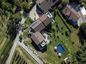 An aerial view of a residential area with multiple houses, a swimming pool, and a road.