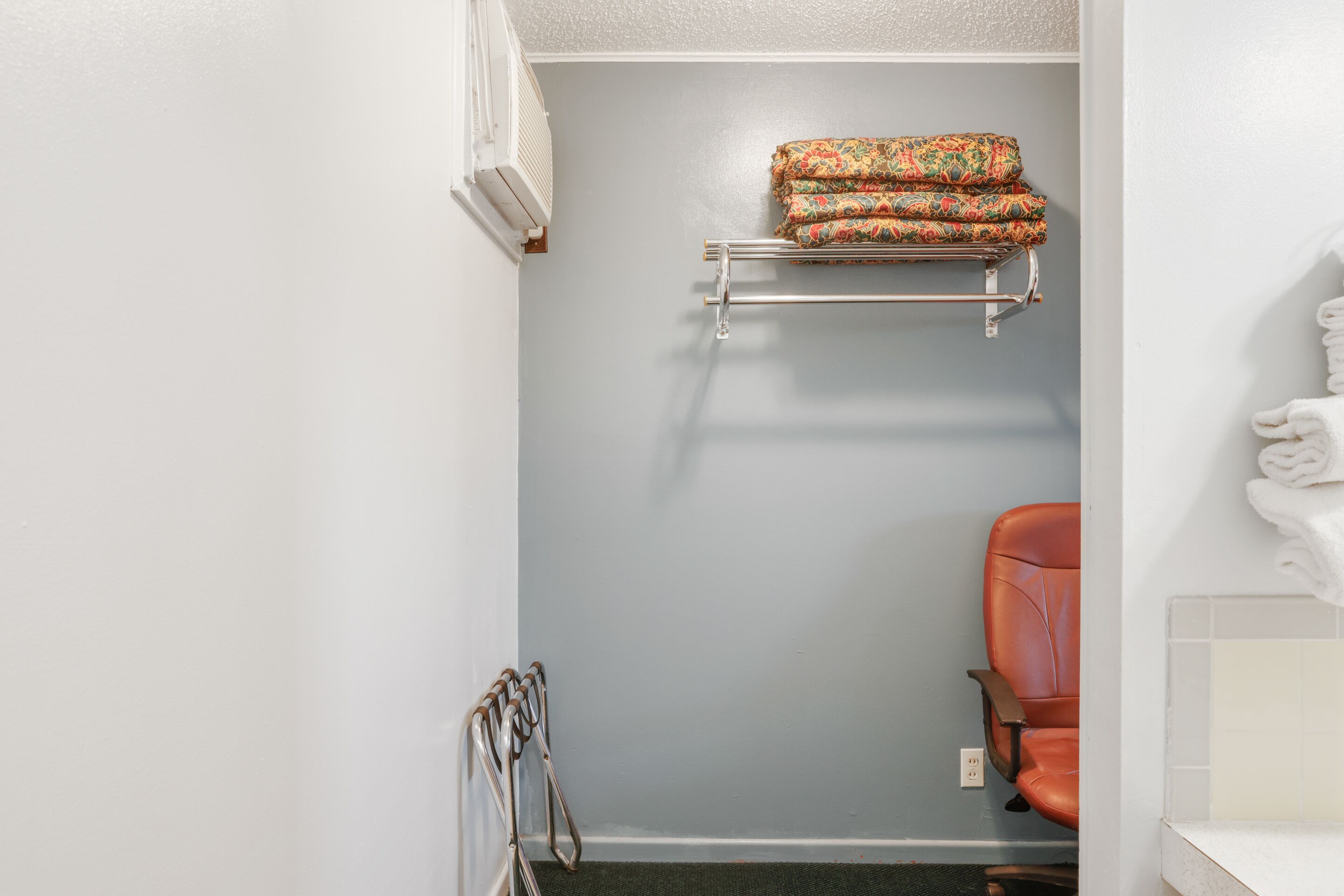 A bathroom with a towel rack, a shower chair, and a towel on the wall.