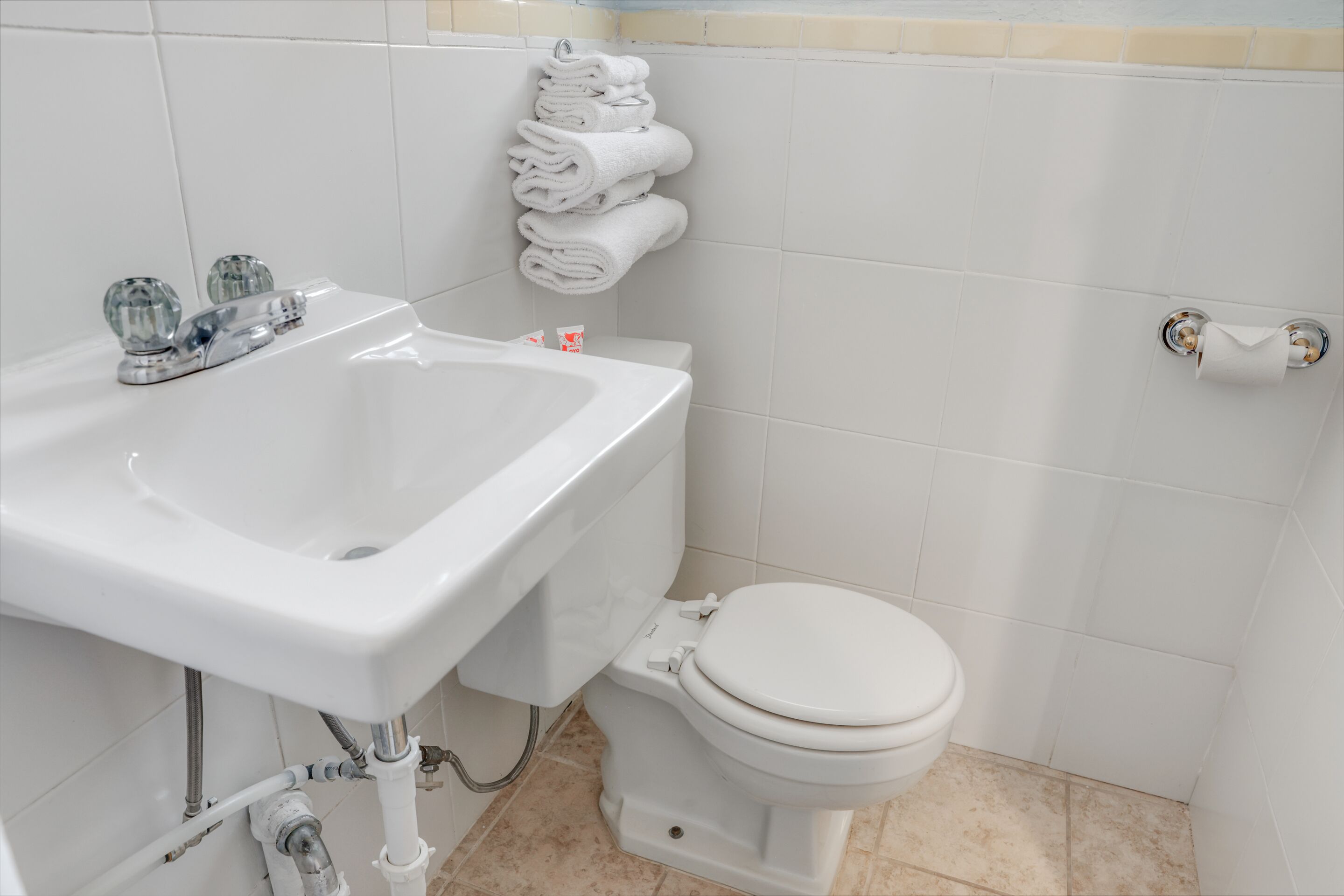A bathroom with a white sink, toilet, and a towel rack.