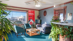 A hotel room with a large window, a ceiling fan, a TV, a coffee table, two sofas, and several potted plants. - OYO Hotel Liberal, Kansas (Liberal)