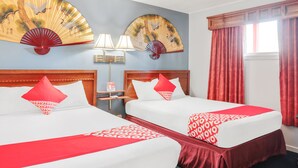 A hotel room with two beds, red and white bedding, a wooden headboard, a nightstand with a lamp, and two wall-mounted fans. - OYO Hotel Liberal, Kansas (Liberal)