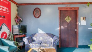 A living room with a sofa, a coffee table, a television, and a clock on the wall. - OYO Hotel Liberal, Kansas (Liberal)
