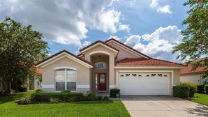A two-story house with a red-tiled roof, a garage, and a well-maintained lawn. - Sunny Retreat by VillaDirect (Davenport)