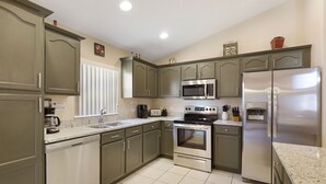 A kitchen with granite countertops, stainless steel appliances, and a dishwasher. - Sunny Retreat by VillaDirect (Davenport)
