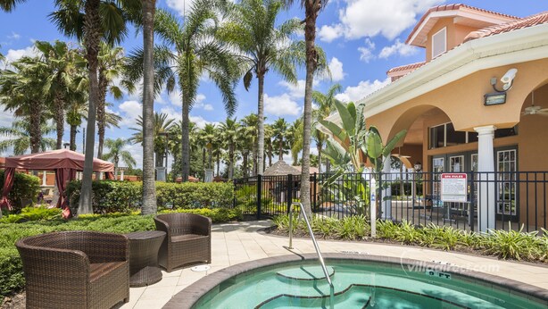 A pool area with wicker furniture, palm trees, and a building with a tiled roof. - Sunny Retreat by VillaDirect (Davenport)