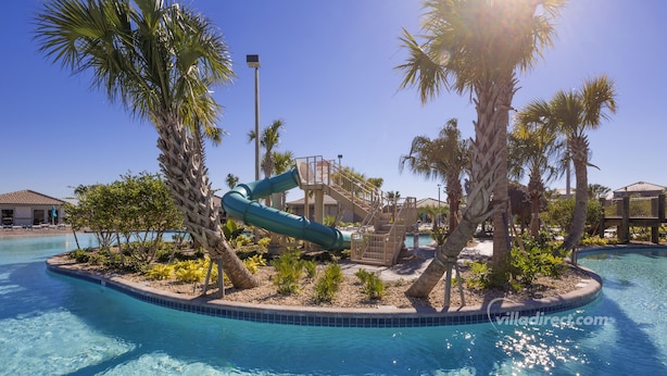 A pool area with a water slide, palm trees, and a clear blue pool.