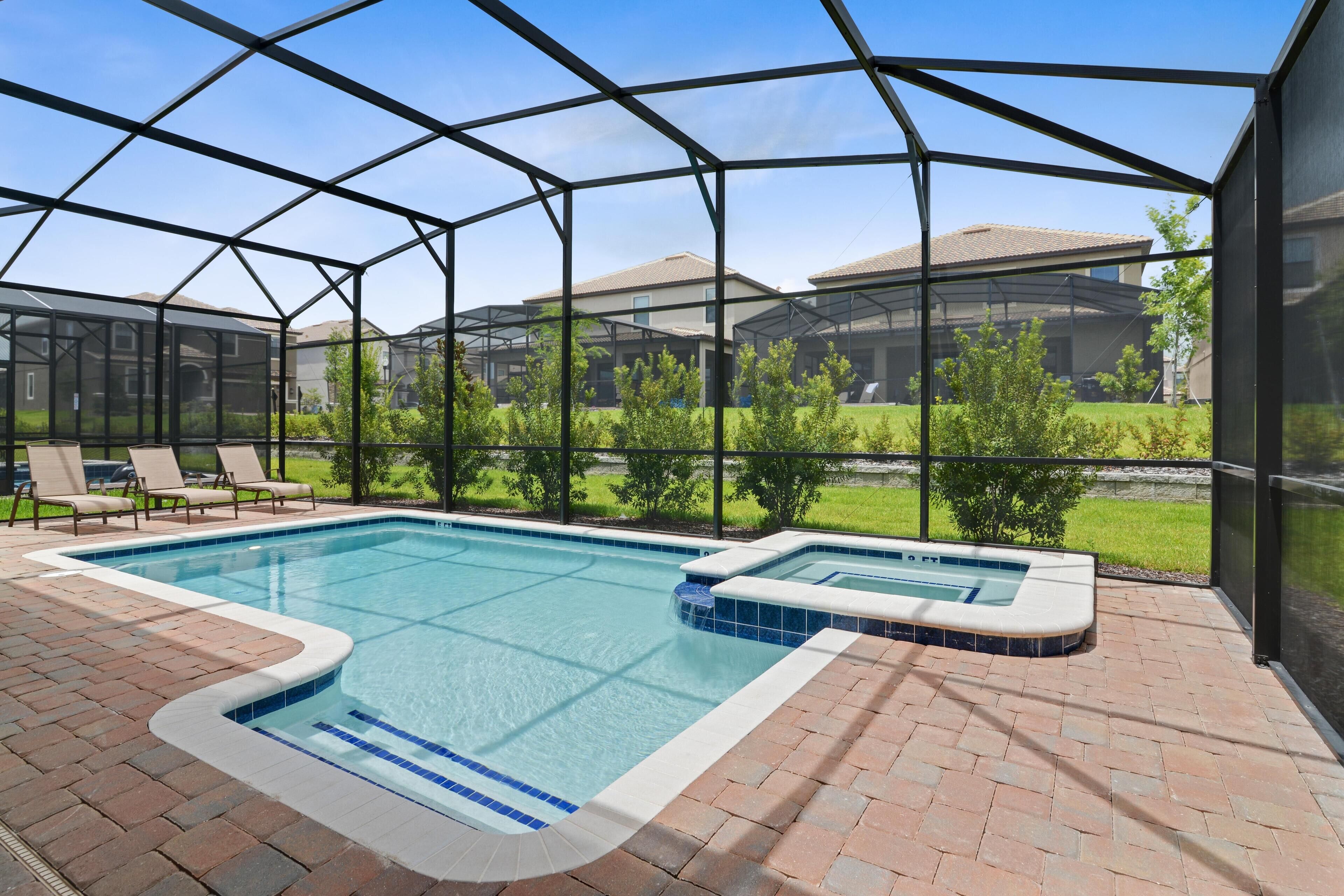 Une piscine intérieure avec un jacuzzi, le tout entouré d’une structure en verre, et un espace extérieur aménagé avec des chaises longues.