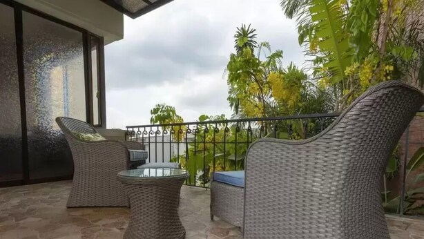 A balcony with wicker furniture, including two chairs and a small table, set on a stone floor. - Casa Orozco (Cali)