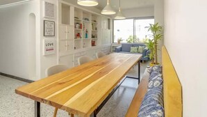 A modern kitchen with a wooden table and bench, white cabinets, and pendant lights. - Casa Orozco (Cali)
