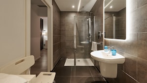 Une salle de bain moderne avec une douche à parois de verre, un lavabo blanc et un grand miroir.