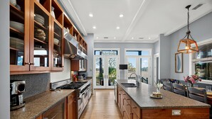 Eine moderne Küche mit Holzschränken, Granit-Arbeitsplatten und einer großen Kochinsel.