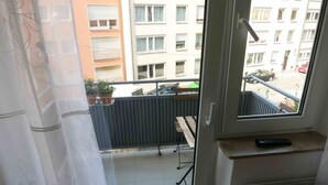 A balcony with a view of a building, a potted plant, and a wooden bench. - Old Town Apartment (Nuremberg)