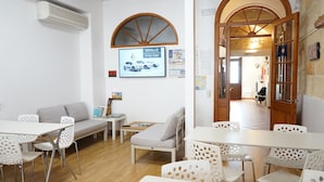 Een moderne kamer met witte meubels, een groot rondboogvenster en een wandairconditioner.