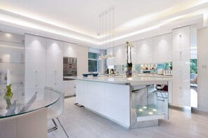 A modern kitchen with a central island, white cabinetry, and pendant lighting.