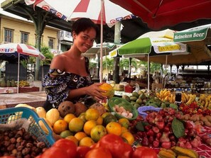 A market stall with various fruits and vegetables, including bananas, apples, and oranges.