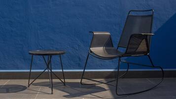 Un juego de silla y mesa de metal negro frente a una pared azul.