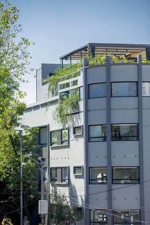 A modern multi-story building with balconies, large windows, and a flat roof.