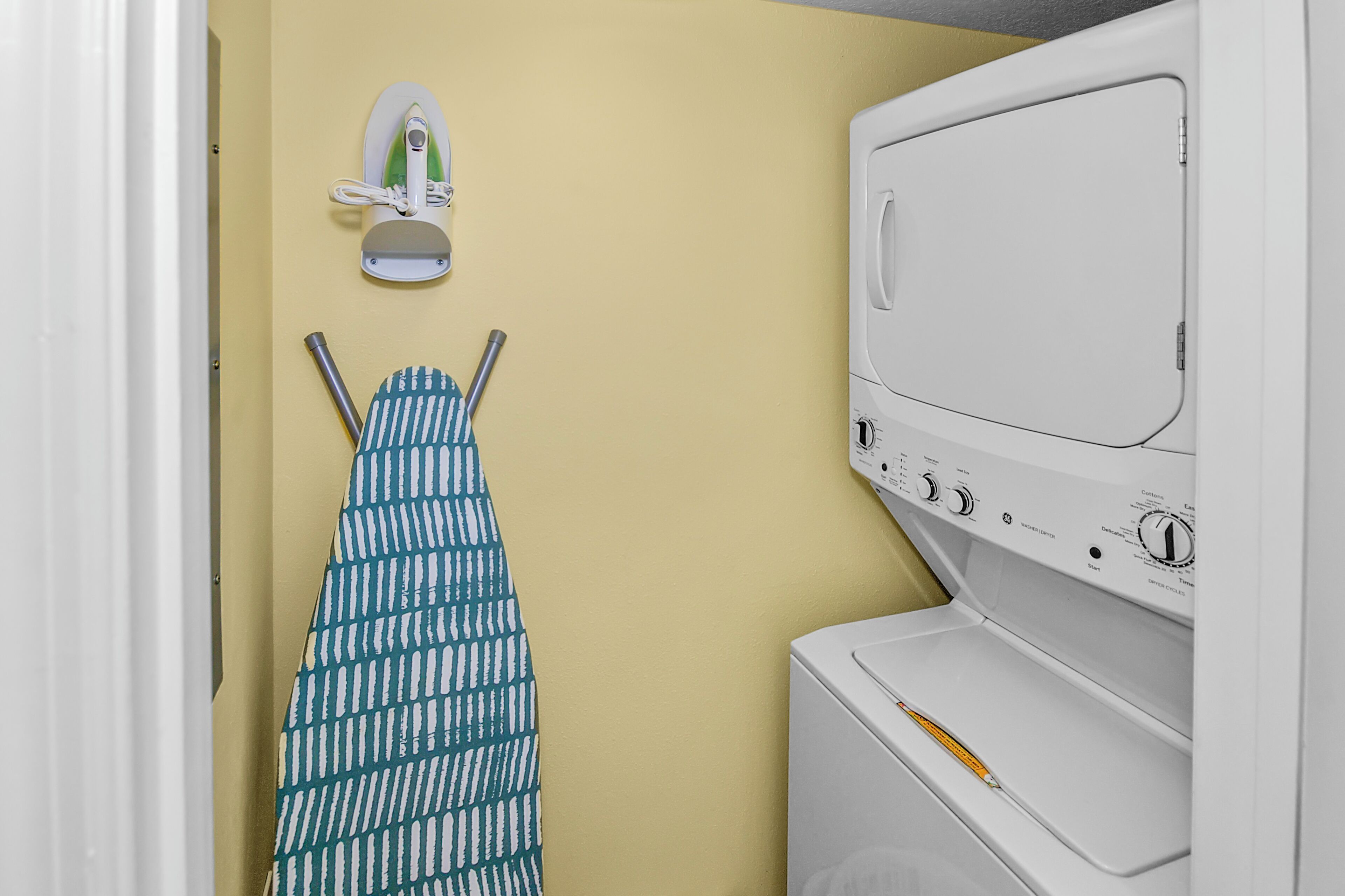 A laundry area with a washing machine, an iron, and a drying rack.