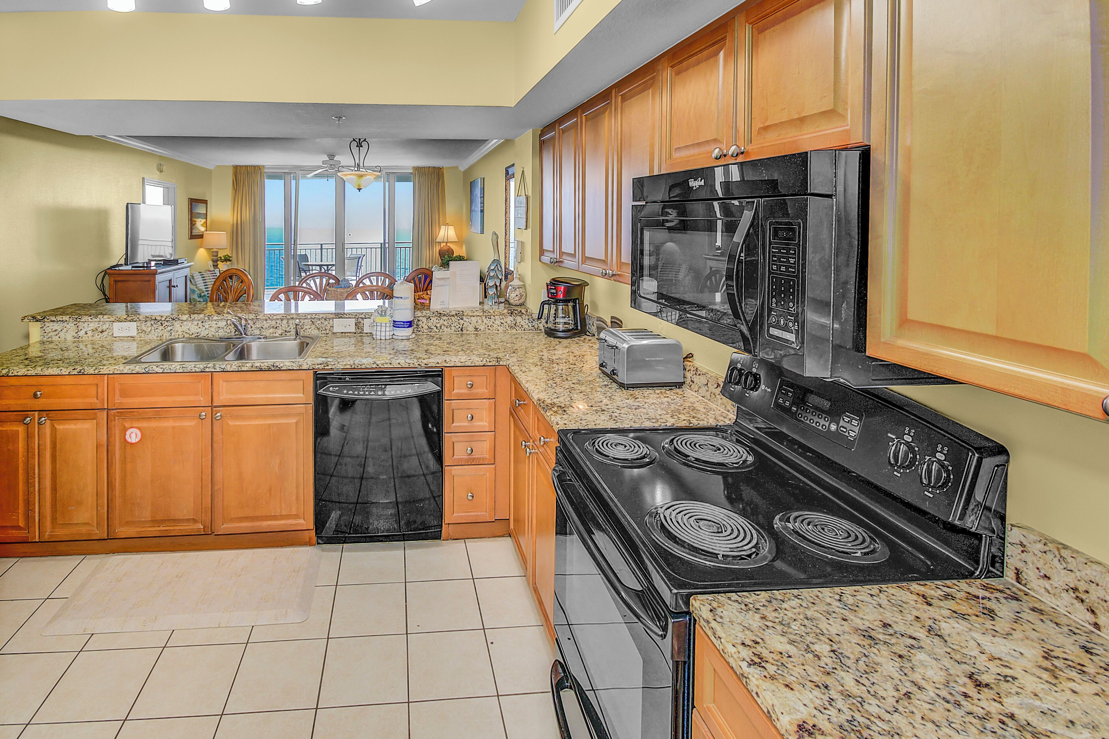 A kitchen with granite countertops, wooden cabinets, a black stove, and a dishwasher.
