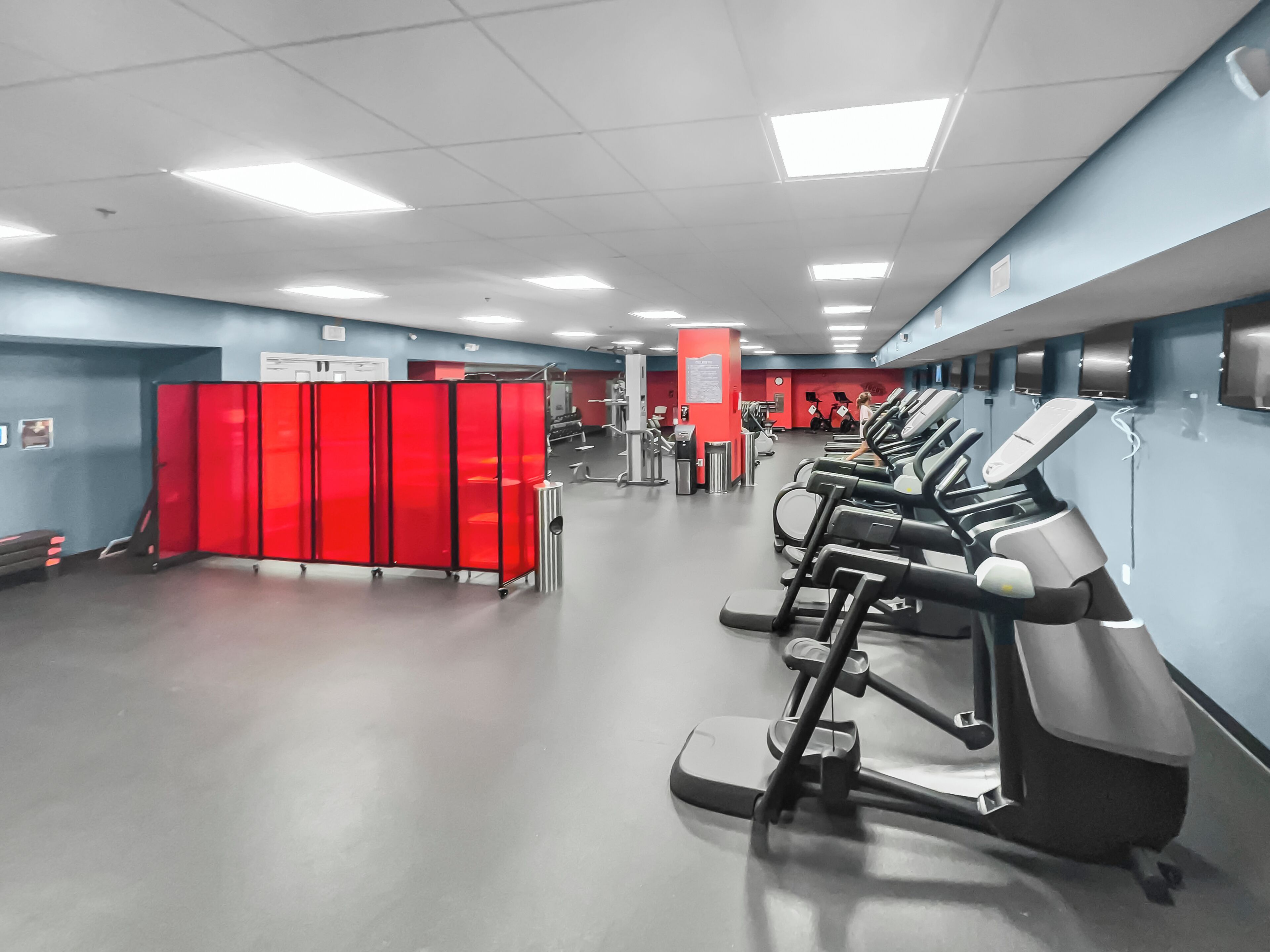 A gym with treadmills, red lockers, and exercise equipment.