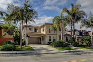 A two-story house with a garage, surrounded by palm trees and a well-maintained lawn.