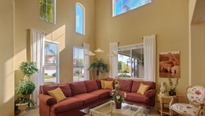 A spacious living room with a large sectional sofa, a glass coffee table, and a decorative chair. - Spacious Oceanside Executive Home Close  to beach (Oceanside)