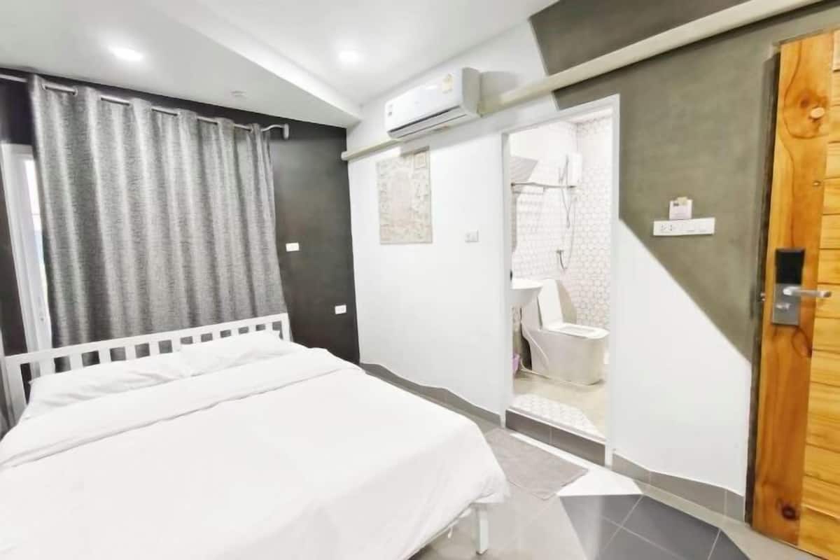 Un dormitorio con una cama, una puerta de madera y un equipo de aire acondicionado.