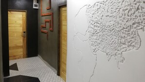 A hallway with wooden doors, a patterned floor, and a textured wall mural. - Hoftors (Bangkok)