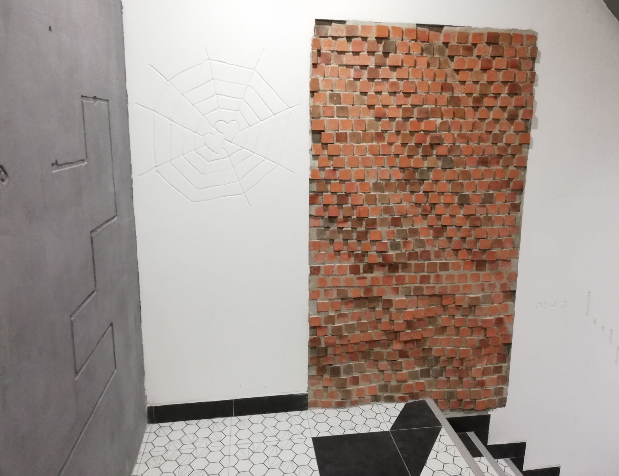 A room with a tiled floor, a brick wall, and a white door.