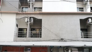 A multi-story building with balconies, air conditioning units, and a storefront with a wooden door and a window with a curtain. - Hoftors (Bangkok)