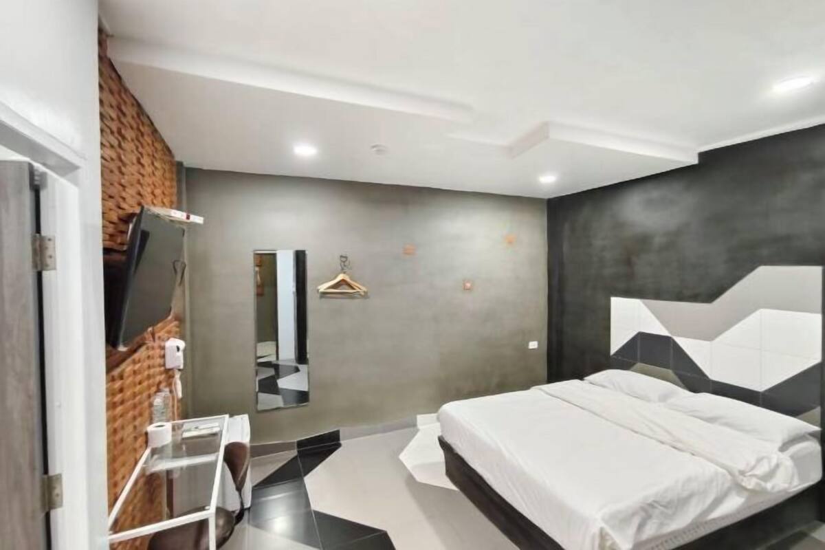 Un dormitorio moderno con cama, escritorio, espejo y lámpara colgante.