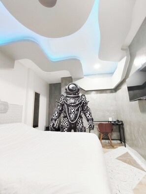 A modern bedroom with a unique ceiling design, a bed, a desk, and a chair. - Hoftors (Bangkok)