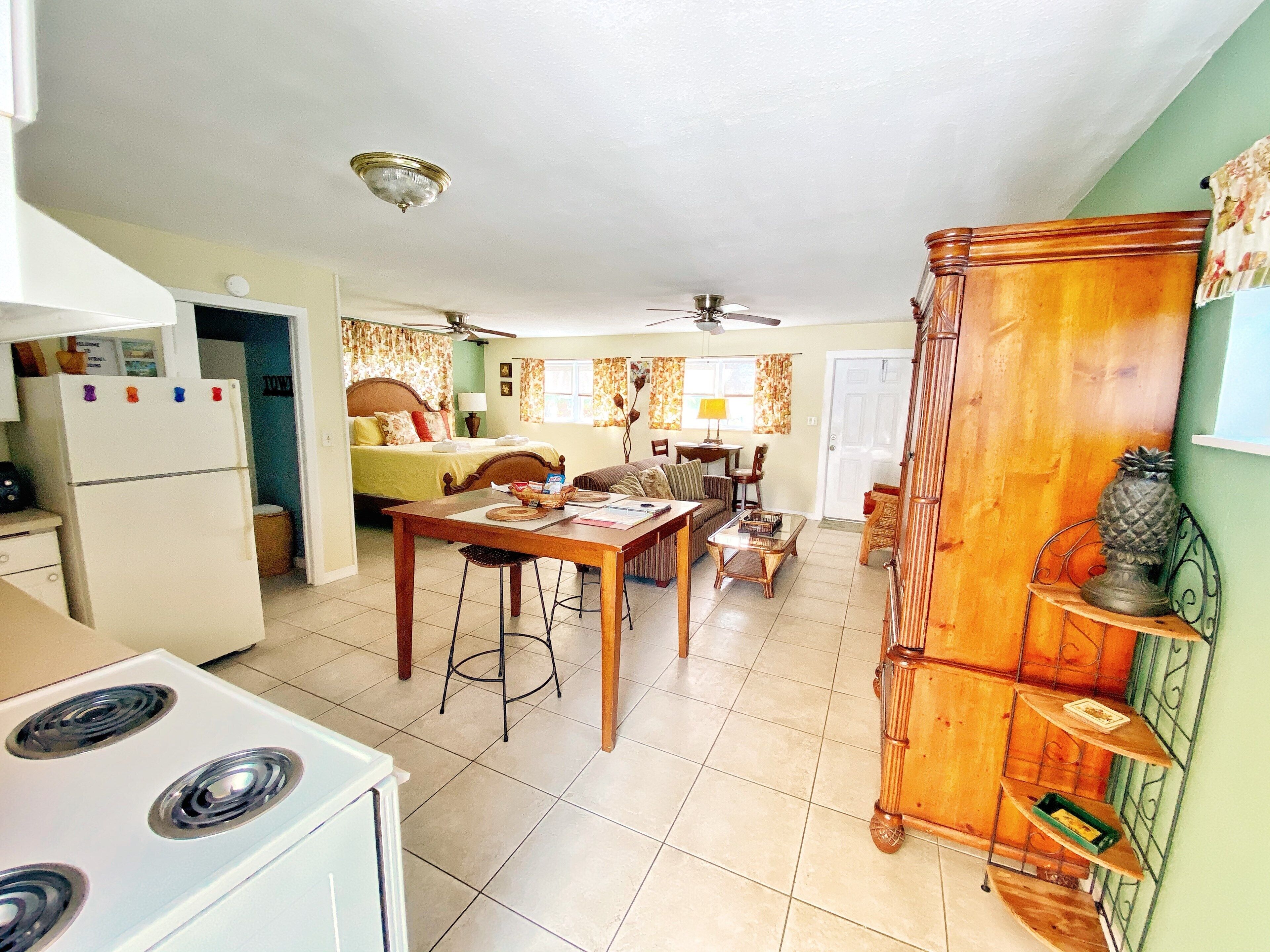 Una cocina compacta con estufa, refrigerador y comedor.