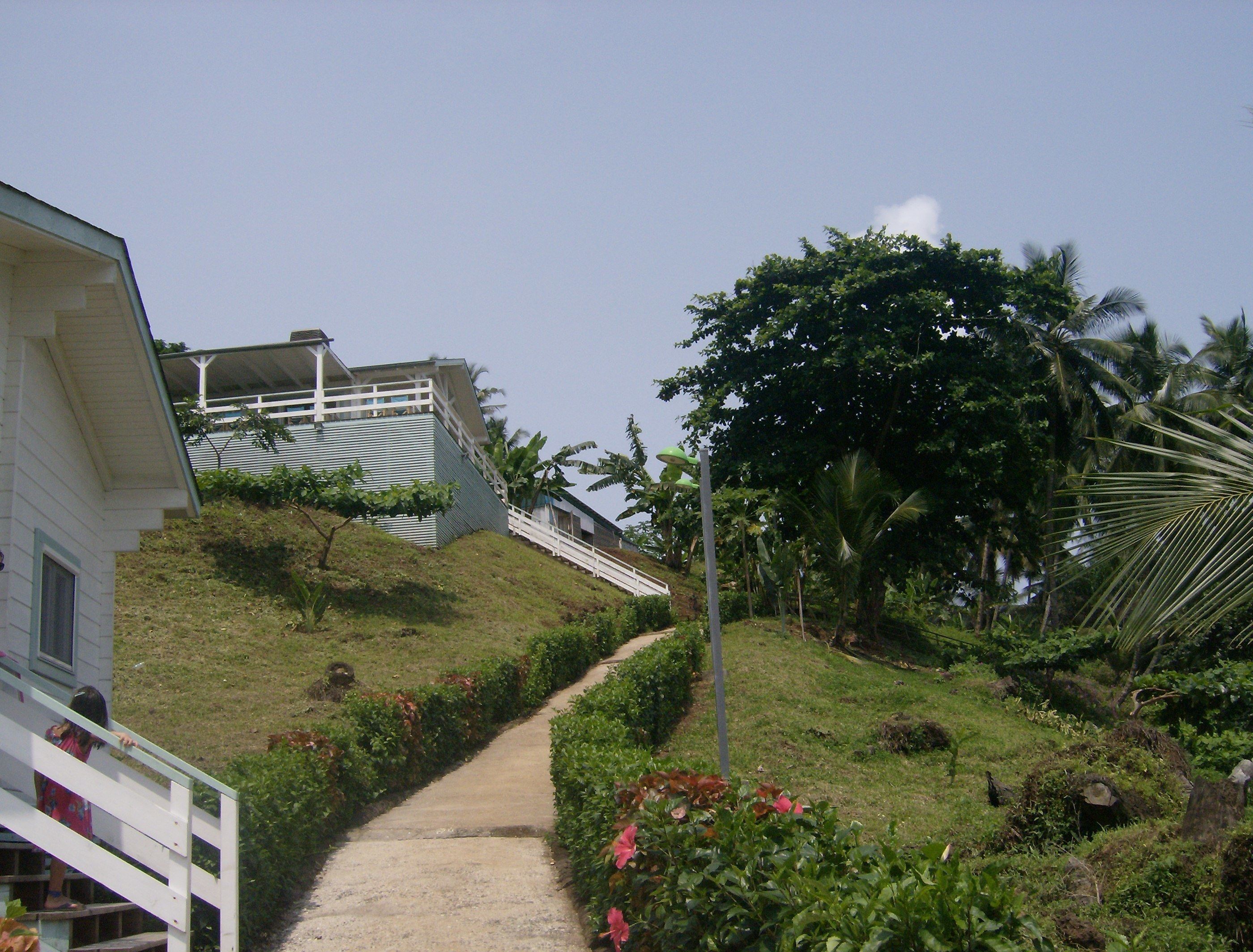 A pathway leading to a building with a white exterior and a balcony.