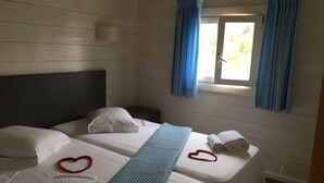 A room with two beds, a window with curtains, and towels on the beds.