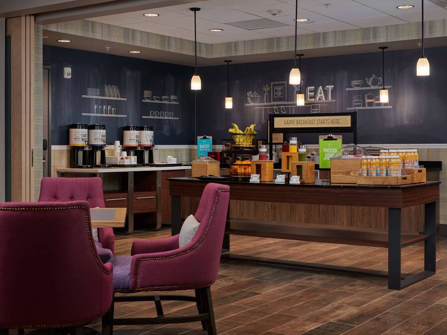 Uma área de café da manhã moderna com balcão, assentos e diversos alimentos e bebidas.